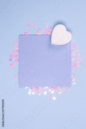 Flat lay background with glitter stars. Pastel blue blank card mockup and white wooden heart on pastel blue background. Scattered glitter stars. Gbar style. photo