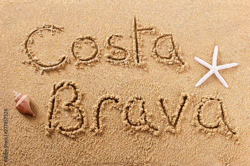 Costa Brava spain word written in sand sign writing drawing drawn on a sunny spanish summer beach with starfish holiday vacation travel destination message photo