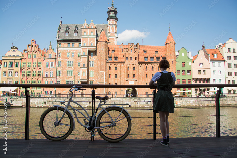 Φωτογραφία Young woman traveler with retro bicycle  stand near river in old gdansk city