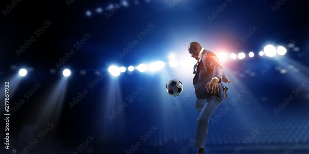 Black businessman in a suit playing footbal