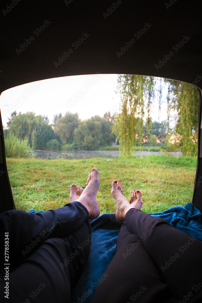 Man and woman relaxing in the trunk of a car near a lake.