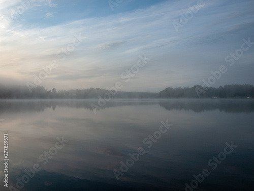 Foggy and mystical lake landscape before sunrise. All silhouettes are blurry and unclear. Vaidavas lake  Latvia