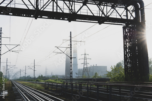 railway tracks going into the fog, pipelines and chimneys in the haze