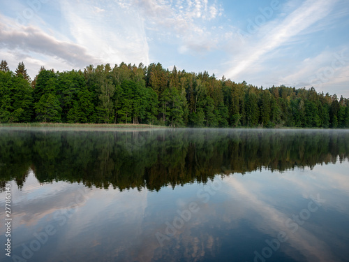 Fototapeta Naklejka Na Ścianę i Meble -  Foggy and mystical lake landscape before sunrise. All silhouettes are blurry and unclear. Vaidavas lake, Latvia