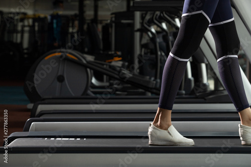 Leg white shoes of slim Fitness woman exercise warm up on push climbing machine elliptical cross in Fit Gym. Concept female Can Do athlete Sport healthy, copy space © Jade