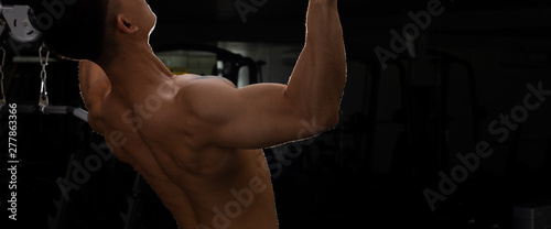 Back side view of Asian Muscular Fitness Man black hair exercise warm up body on Pull up machine Weight Muscle Hands Arms bodybuilder trains triceps in Fit Gym. Concept male Can Do athlete healthy