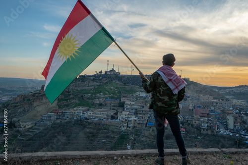 Teenager holding the Kurdistan flag in northern Iraq at sunset time on Nowruz 2019 photo