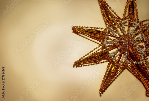Christmas star made of gold colored glass lies on a gold background