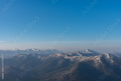 Panoramic view of beautiful mountain landscape  snowy mountain peaks covered by forest with a dark blue clear sky background in spring time sunny day