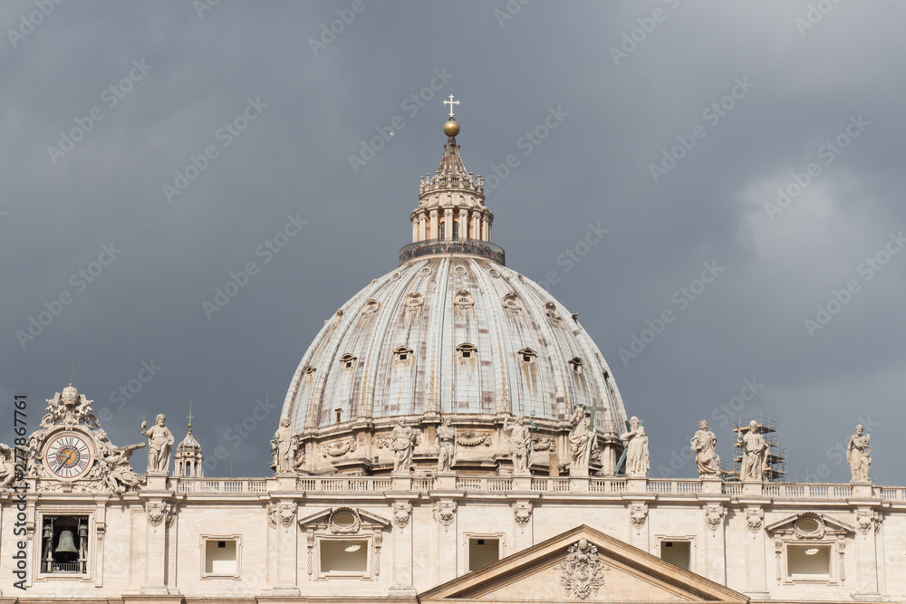 Close up view of St. Peter's Basilica Dome with rainy clouds on background, Vatican city state, Italy.
