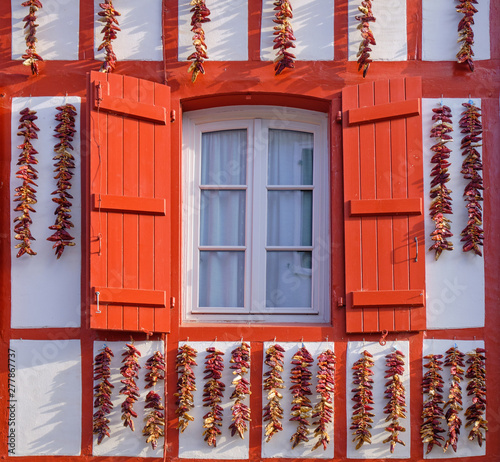 Espelette facade light up by high sun, with typical basque geometric architecture and local peppers hung to dry on facade photo