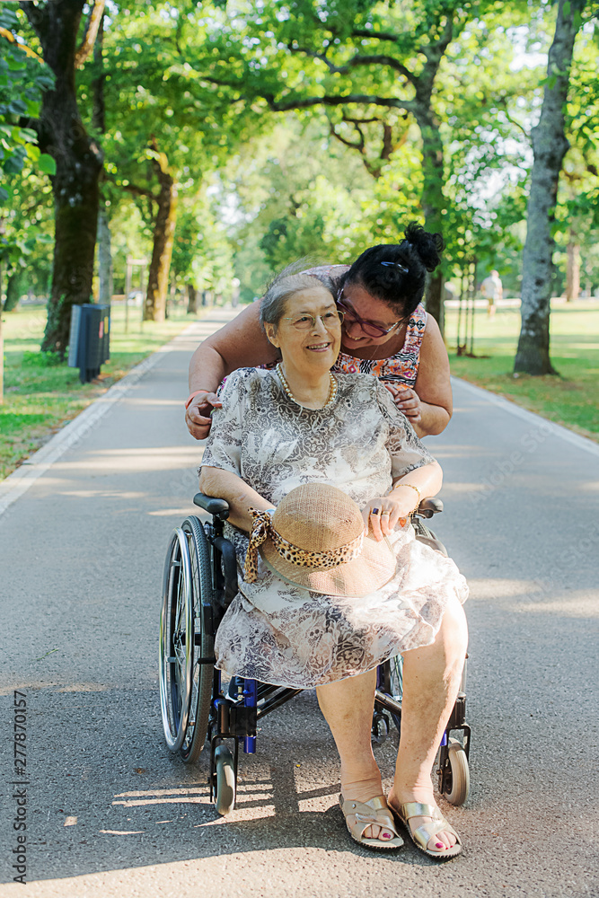 senior lady in wheelchair with care giver in outdoors senior lady in wheelchair with care giver in outdoors