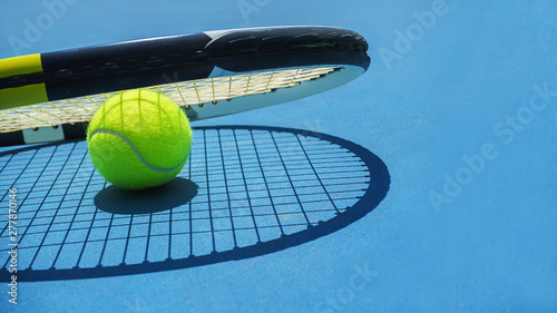 Summer sport concept with tennis ball and racket on blue hard tennis court. Top view, copy space. Blue and yellow. Banner size. © IrynaV
