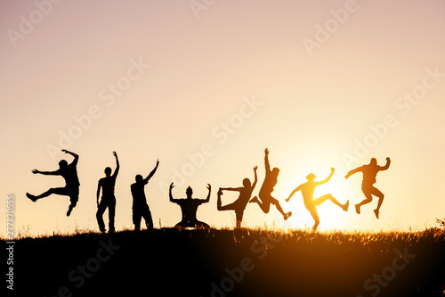 Silhouettes of big group of friends jump and fun