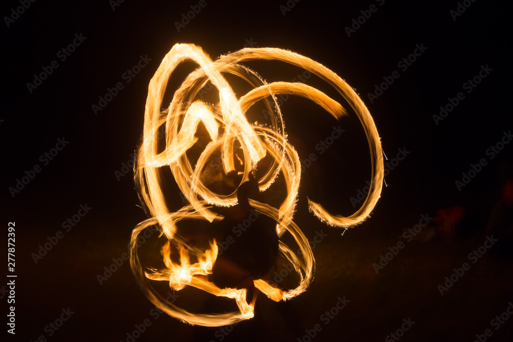 The artist shows a fire show at night spinning torches, circles of fire ...