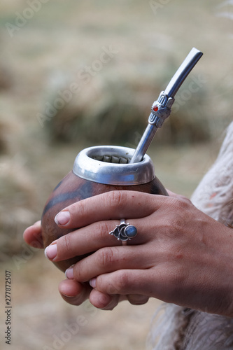 Womans hands holds traditional calabash gourds for yerba mate on the wooden surface, selective focus photo