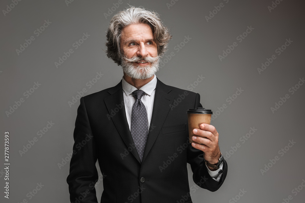 Image of joyful adult businessman wearing formal black suit smiling and holding paper cup Image of joyful adult businessman wearing formal black suit smiling and holding paper cup