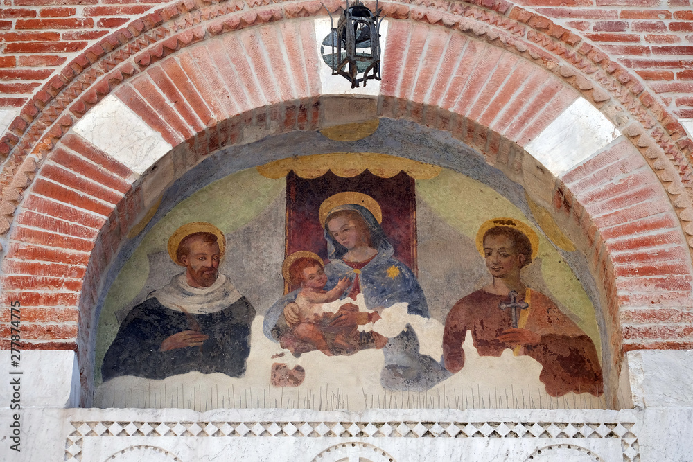 Virgin Mary with baby Jesus and Saints, lunette over the entrance door to the Sant Anastasio church in Lucca, Tuscany, Italy 