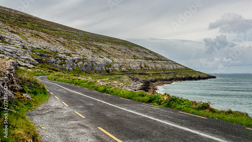 Beautiful view of the rural coastal R477 road along ​​the Burren, geosite and geopark, Wild Atlantic Way, cloudy spring day in county Clare, west coastal of Ireland photo