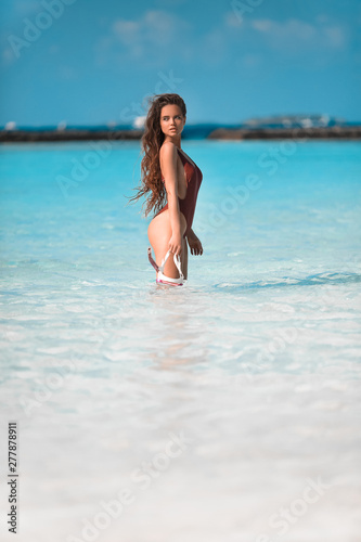 Sexy model on Beach vacation. Happy fun girl holding snorkel scuba mask standing in ocean water. Maldives summer. Young woman enjoying life.