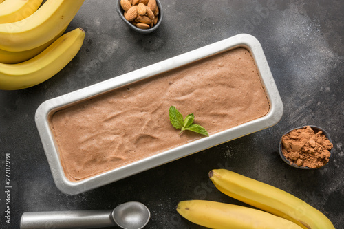 Banana chocolate homemade ice cream in container with coffee beans on black. Top view. photo