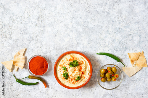 Healthy homemade hummus served with paprika powder, pita bread, olives and parsley. Middle Eastern cuisine, Israeli cuisine, Levanese cuisine, Levantine cuisine. Light background. Top view