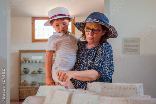 Mother son in museum looking at a reconstructed model. Summer holidays. Woman holding boy in her hands indoor. Two persons in hats standing indoor. Happy childhood concpet. Happy motherhood photo