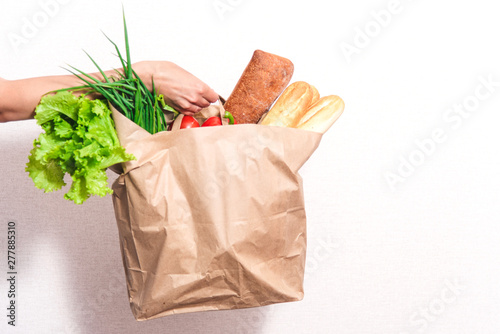 beautiful smiling woman holding a bag of groceries, standing on an isolated white background