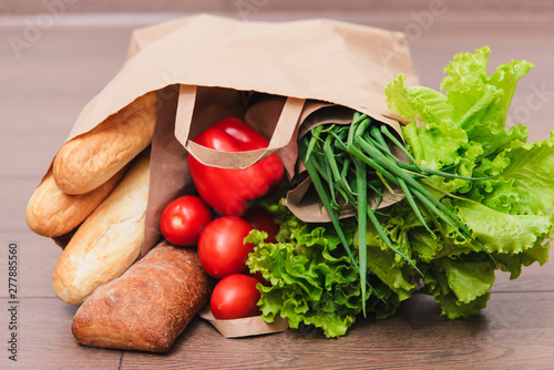 beautiful smiling woman holding a bag of groceries, standing on an isolated white background