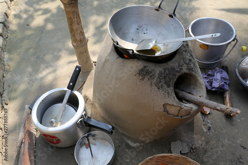 Mud kitchen stove in village outside home. Remnants of firewood, ashes and matches. The pot will be set on top of the round opening, Kumrokhali, West Bengal, India. photo