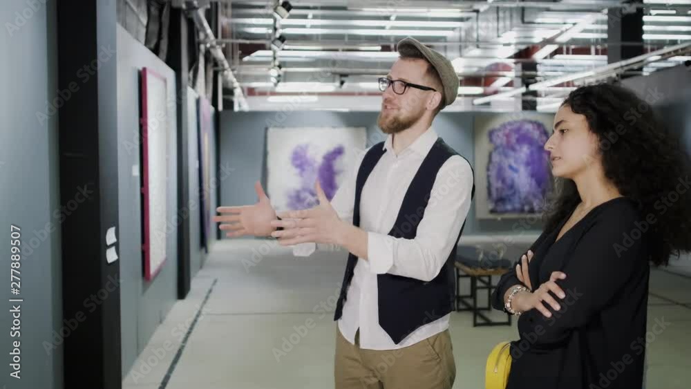 Excited man and bored woman are standing in front picture in hall of museum Excited man and bored woman are standing in front picture in hall of museum