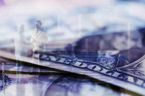Double exposure row of coins of Two Business man and graph,saving,investment and finance concepts. Miniature people Stand in front of a coin,soft focus and blurred style. © Chunnapa