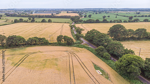 An aerial view of countryside panorama with fields, trees,forest and rural road under a stromy sky and shady sun