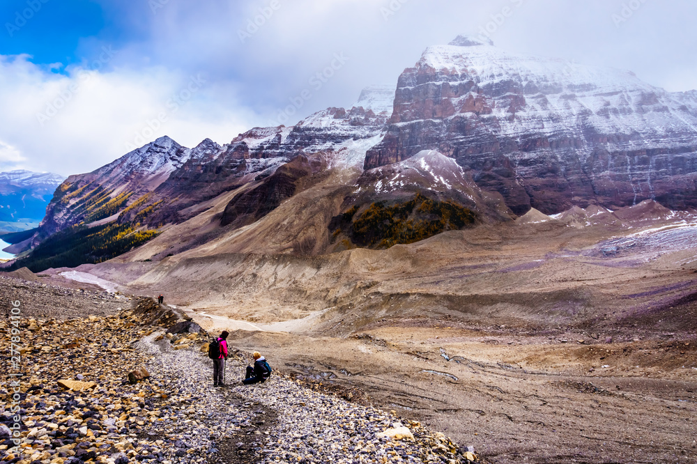 Senior women hiking and falling on the moraines of the Victoria Glacier from the Plain of Six Glaciers Teahouse to the to the Six Glaciers at Lake Louise in Banff National Park, Alberta, Canada