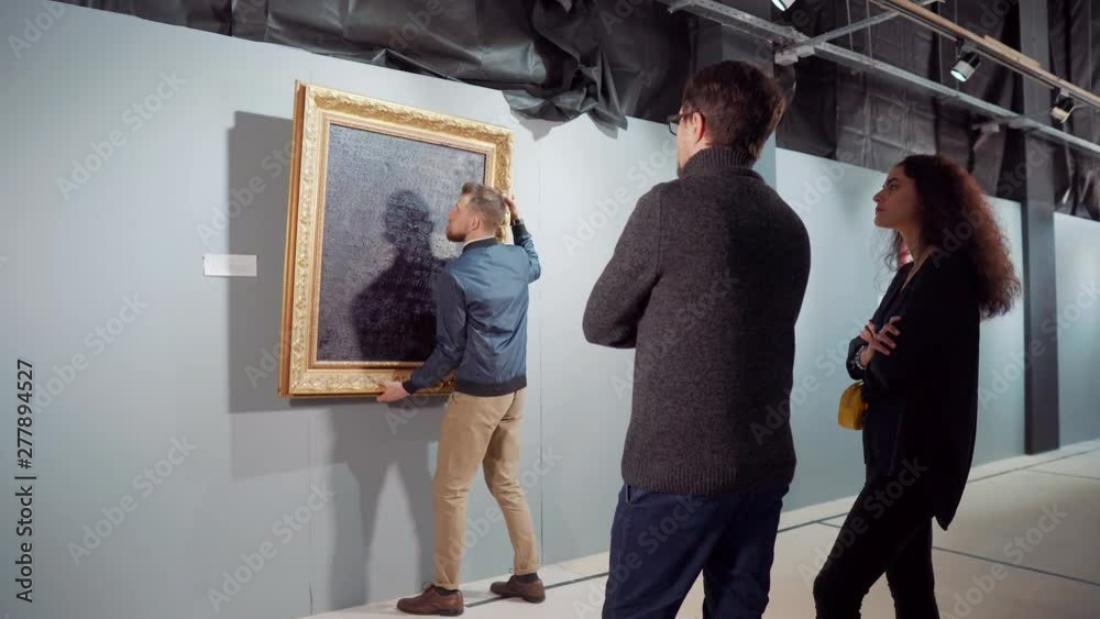 Viewing Something People are viewing picture in gallery, worker is carrying off it from ...