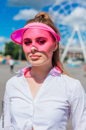 Portrait of an emotional girl in a pink cap visor and protective gloves for rollerblades and skateboarding. © Smile