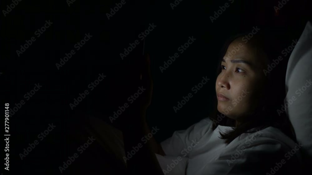 Asian woman playing game on smartphone in the bed at night,Thailand people,Addict social media Asian woman playing game on smartphone in the bed at night,Thailand people,Addict social media