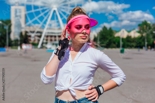 Portrait of an emotional girl in a pink cap visor and protective gloves for rollerblades and skateboarding.