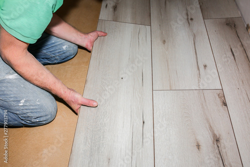 Worker making laminate flooring in apartment. Maintenance repair renovation. Wooden parquet planks indoors.