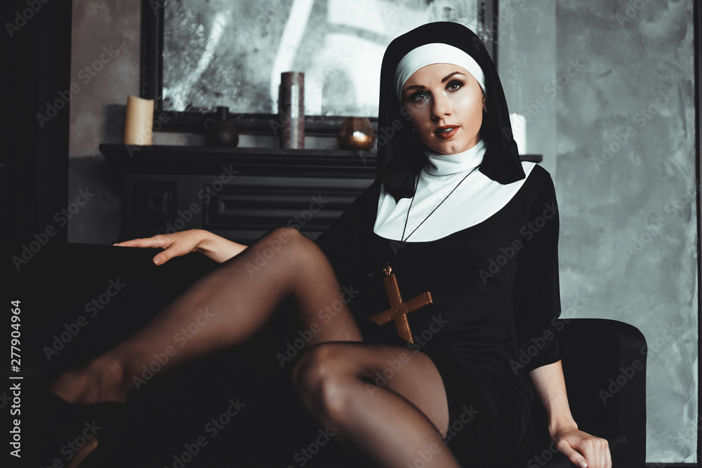 Sexy nun prays indoor . Beautiful young holy sister. Young beautiful nun  with a cross in a robe in a black interior. foto de Stock | Adobe Stock