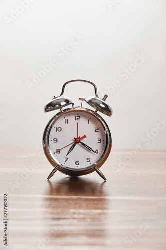 silver alarm clock on wooden table isolated on grey