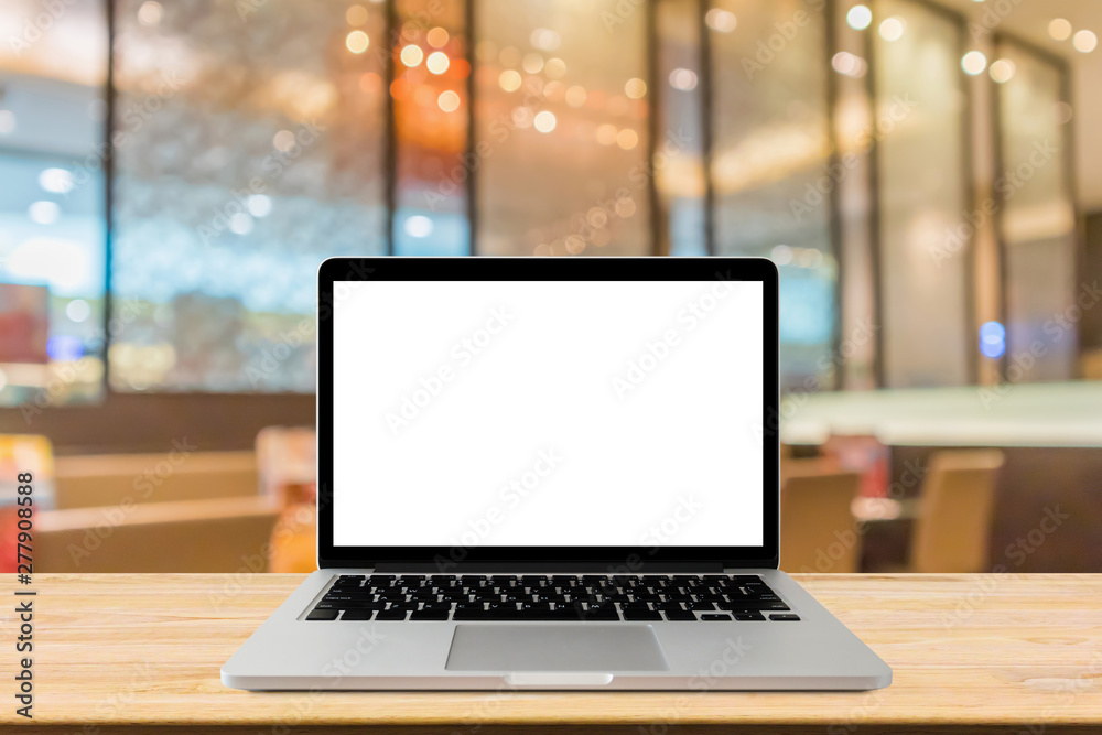 Blank screen laptop computer on wood table top with blur cafe restaurant with abstract bokeh light defocused background Blank screen laptop computer on wood table top with blur cafe restaurant with abstract bokeh light defocused background