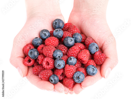 Female hand holding raspberries and blueberries. Red raspberries and blueberries in hands on a white isolated background