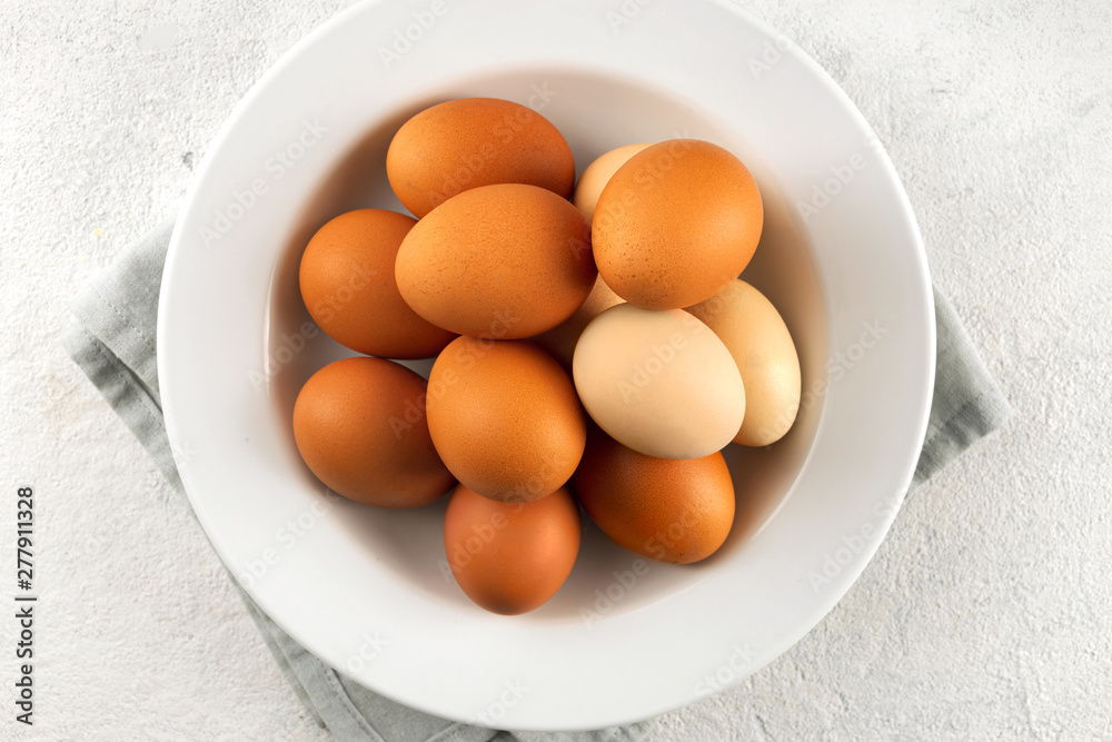 Brown eggs in plate on a white background with copy space top view