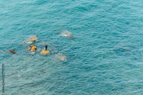 Aerial view of Fisherman standing on the stones amid the sea wave for fishing in Chonburi, Thailand. © artitwpd