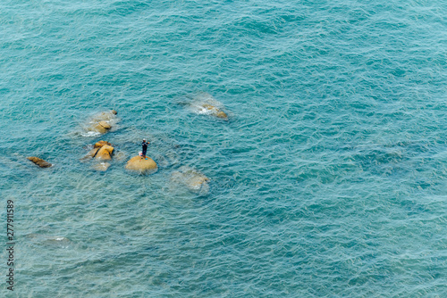 Aerial view of Fisherman standing on the stones amid the sea wave for fishing in Chonburi, Thailand.