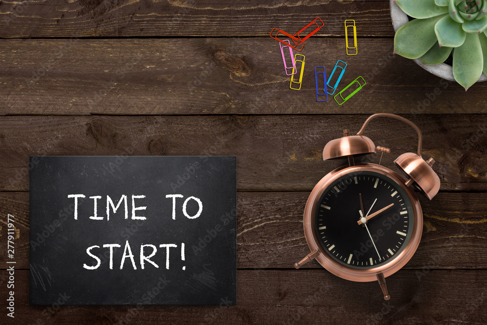 Alarm clock next to slate plate with text "Time to start!" on wooden background - obrazy, fototapety, plakaty 