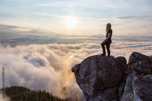 Adventurous Female Hiker on top of a mountain covered in clouds during a vibrant summer sunset. Taken on top of St Mark s Summit  West Vancouver  British Columbia  Canada.