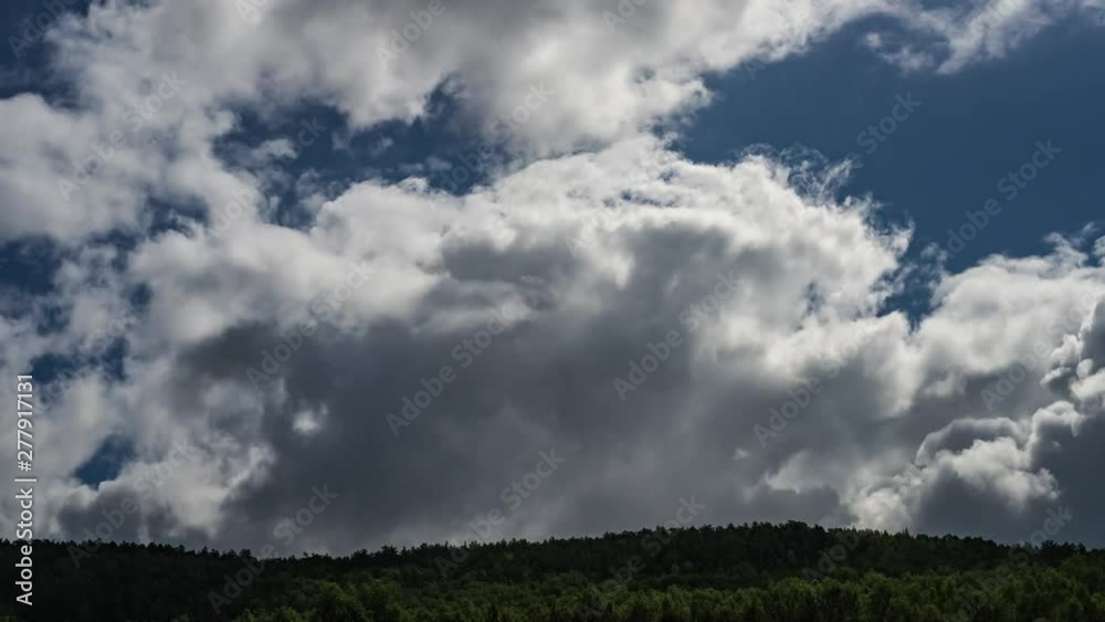 Clouds in blue sky moving and changing shape above the green coniferous forest. 4K UHD Time-Lapse Video Clouds in blue sky moving and changing shape above the green coniferous forest. 4K UHD Time-Lapse Video