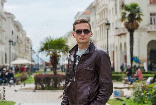 Young handsome man in sunglasses, tourist, on the pedestrian Aristotle Street in the center of the Thessaloniki, Greece